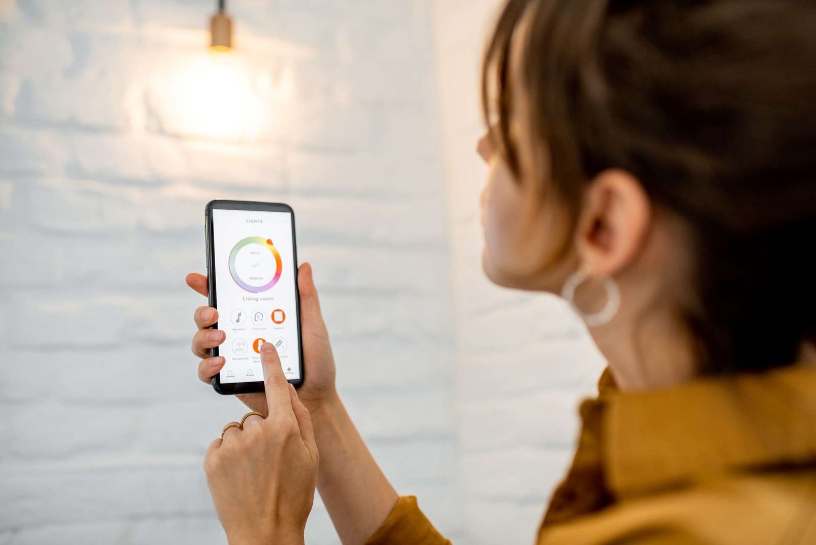 Frau mit einer Smart-Home App bedient Licht in ihrem Haus